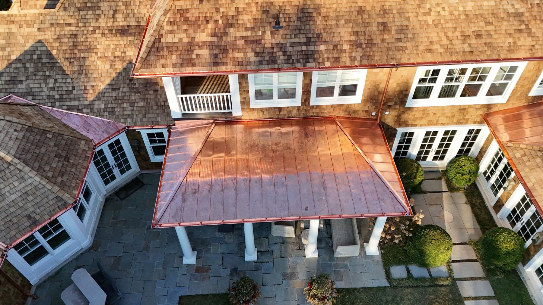 Standing seam copper porch roof beneath natural cedar shingles