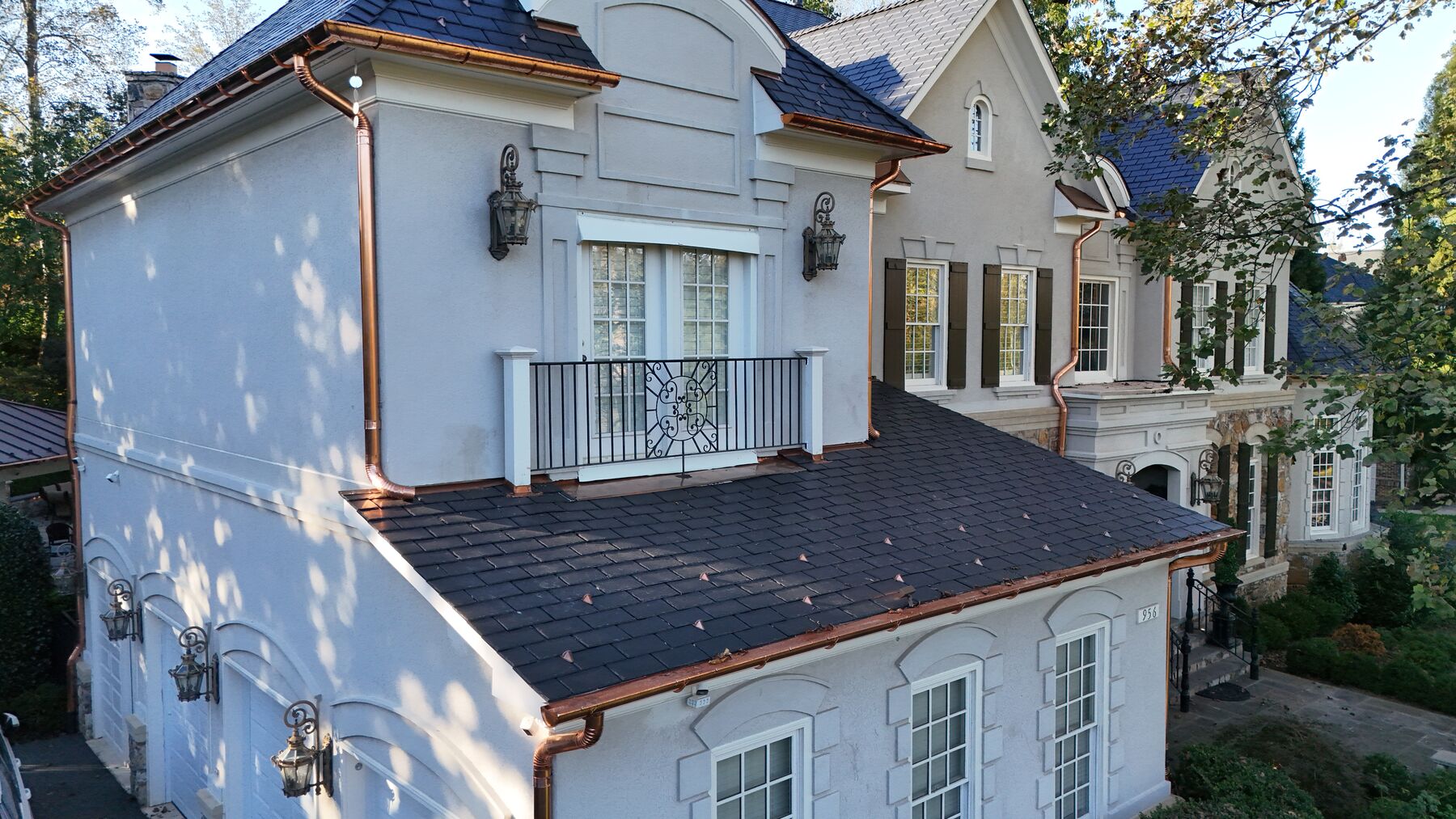 French country home with black slate roof and copper gutters and downspouts