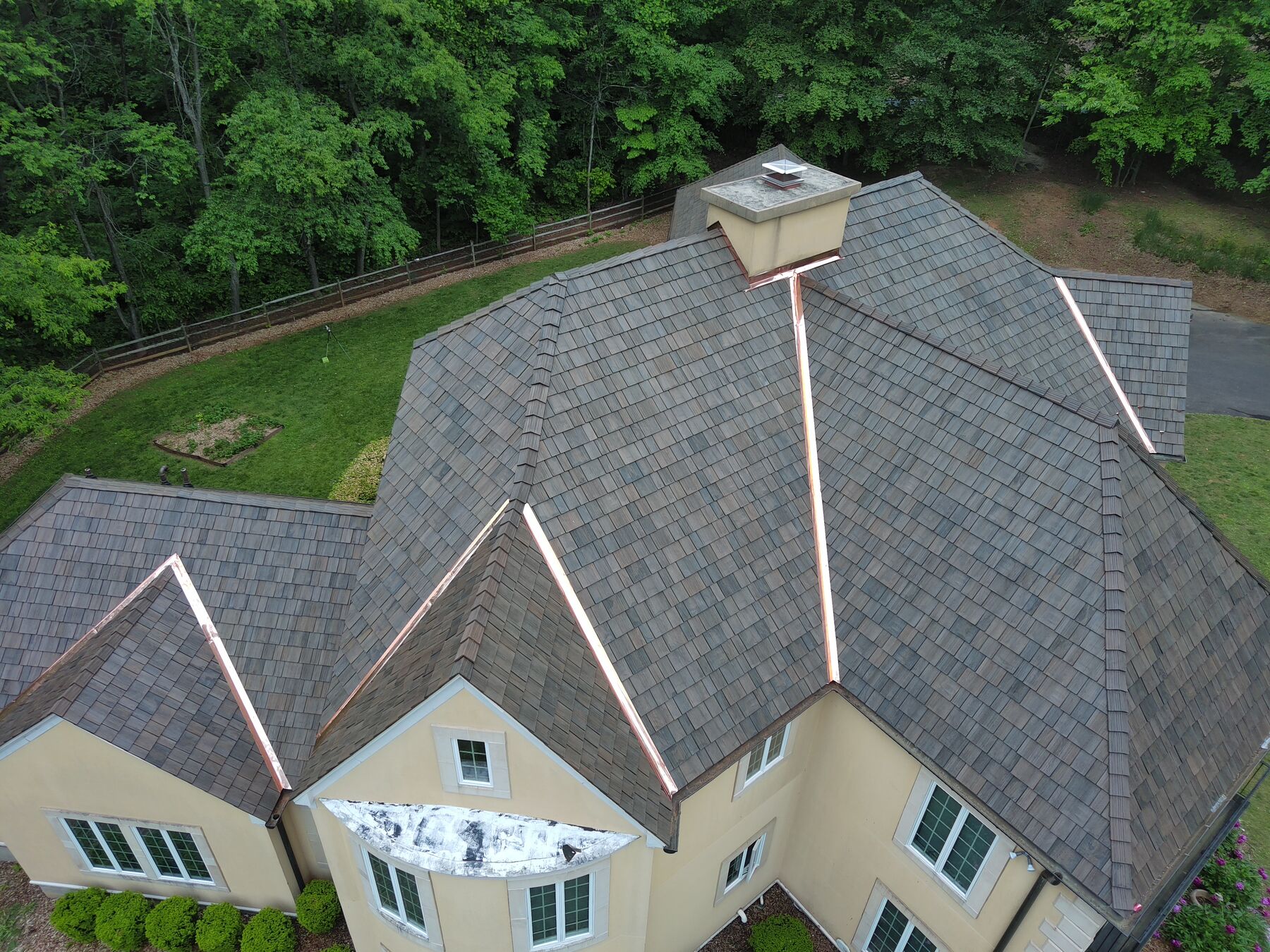 Brava synthetic shake roof with copper ridge caps and valleys on a stucco estate