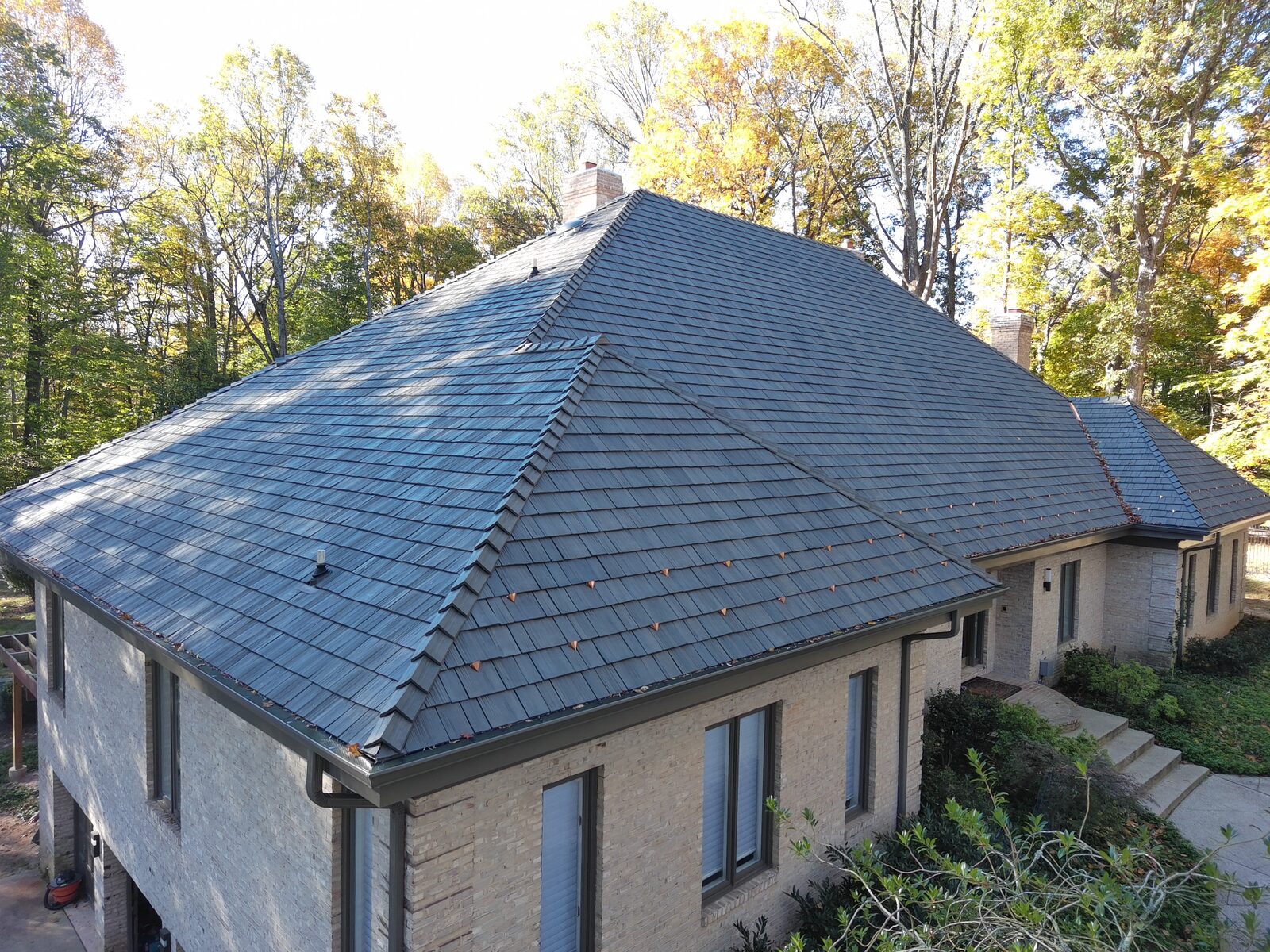 Aerial view of a brick home with a slate-gray Brava synthetic shake roof