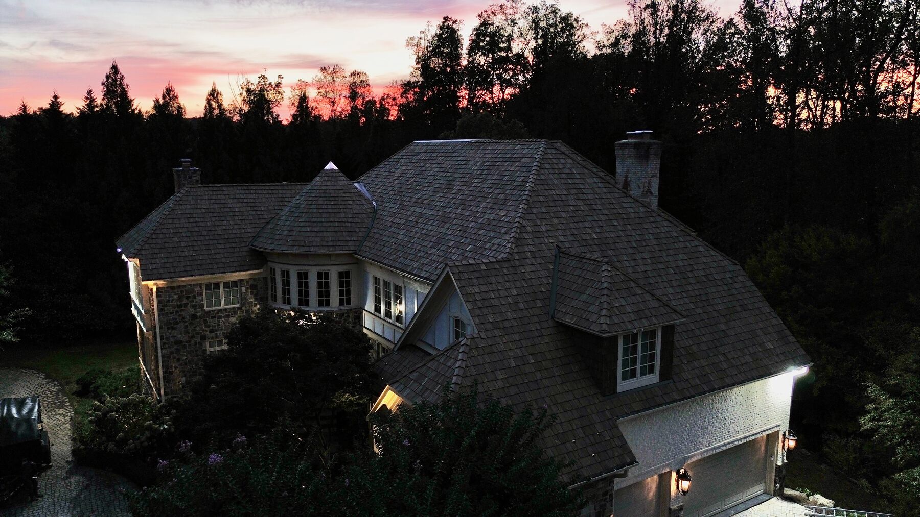 Stone and timber home with a new Brava synthetic shake roof at sunset