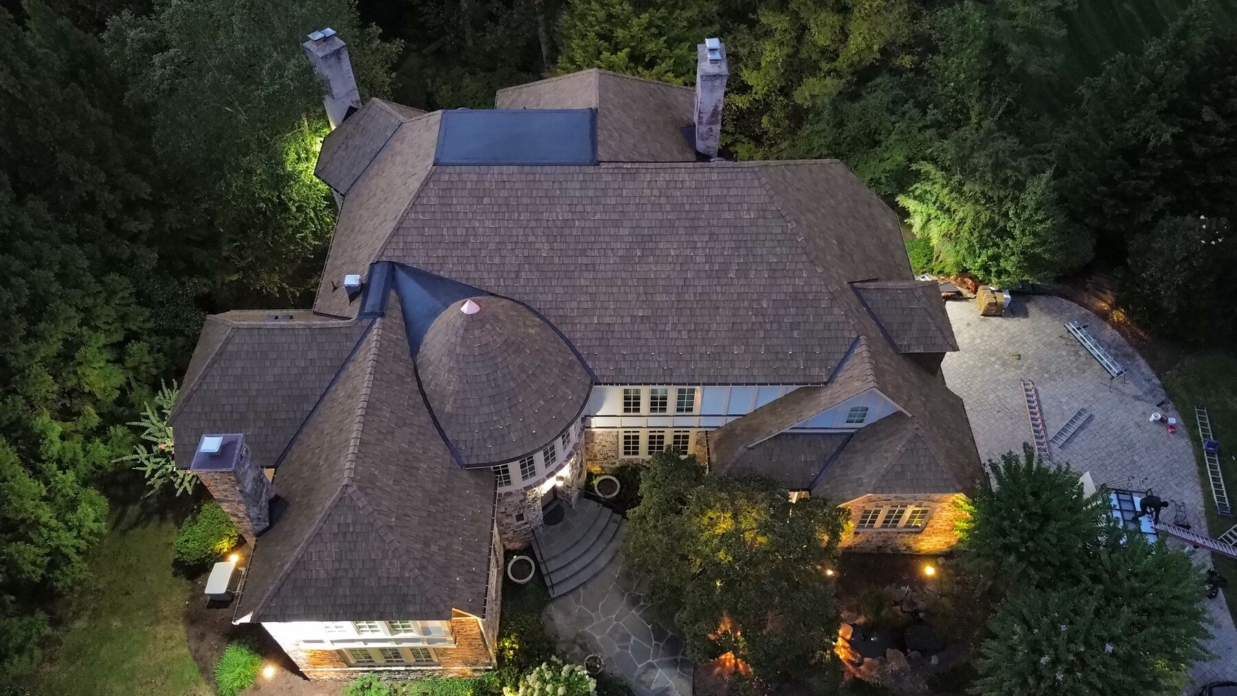 Evening aerial of a Brava synthetic shake roof with a cone turret and copper finial