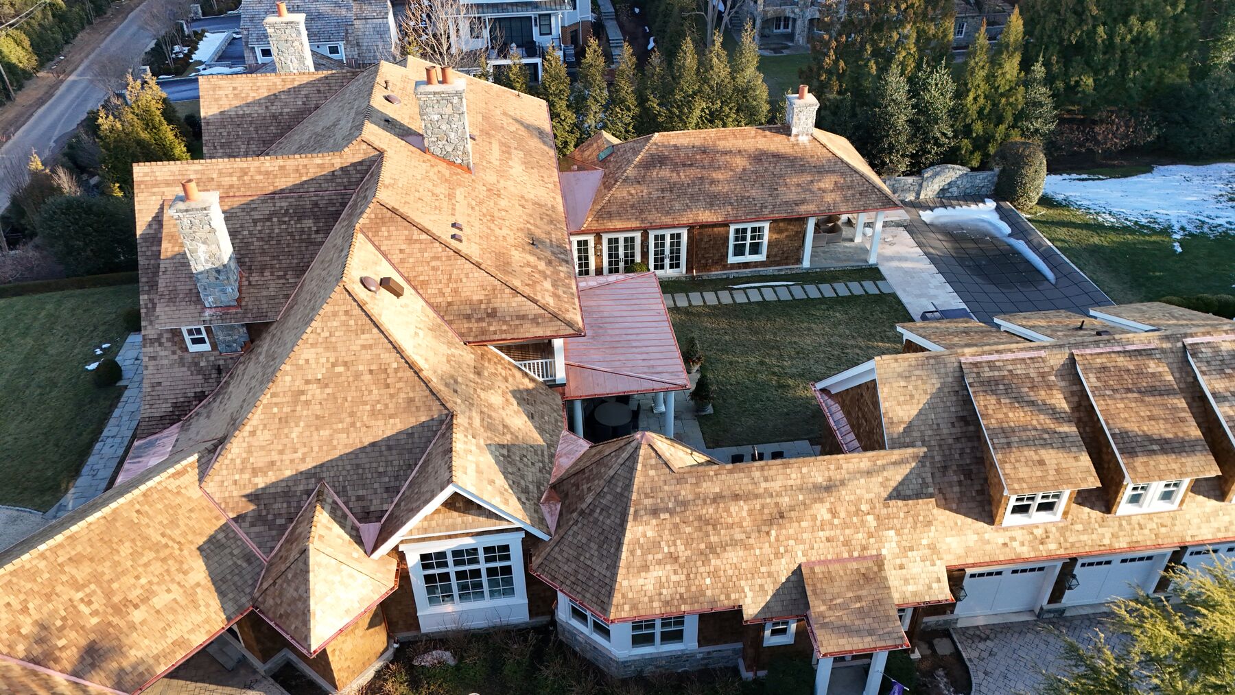 Estate with natural cedar shake roof and standing seam copper porch roof