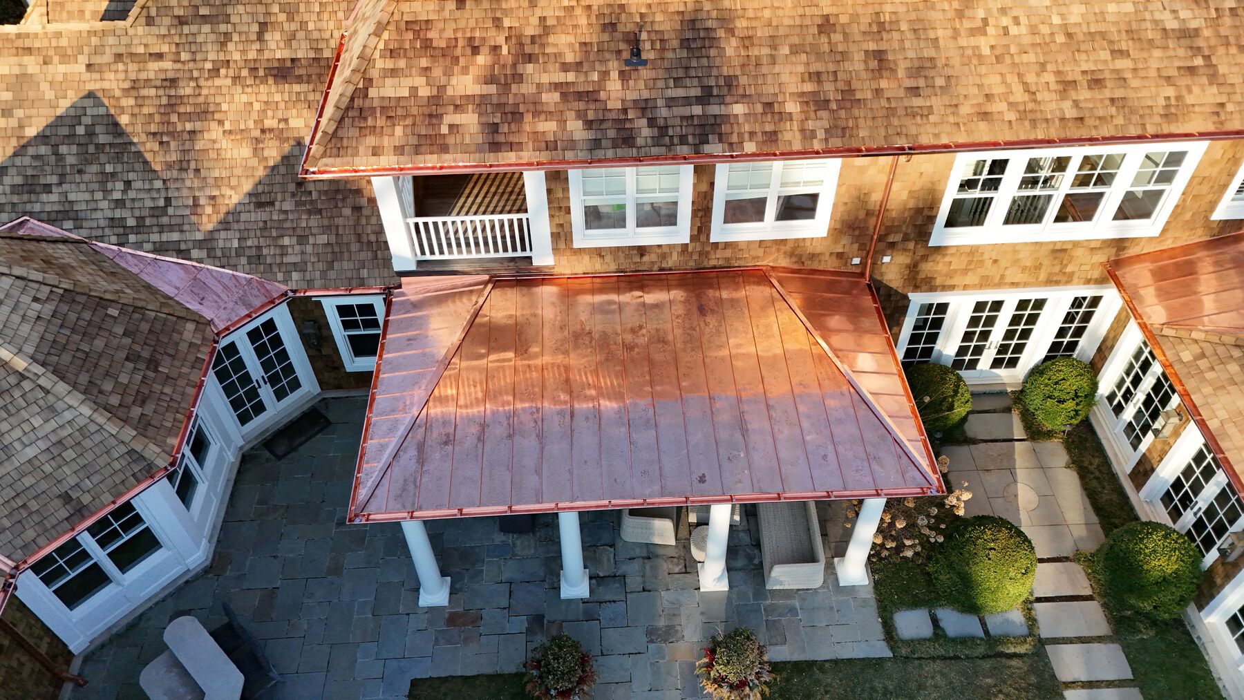 Standing seam copper porch roof beneath natural cedar shingles