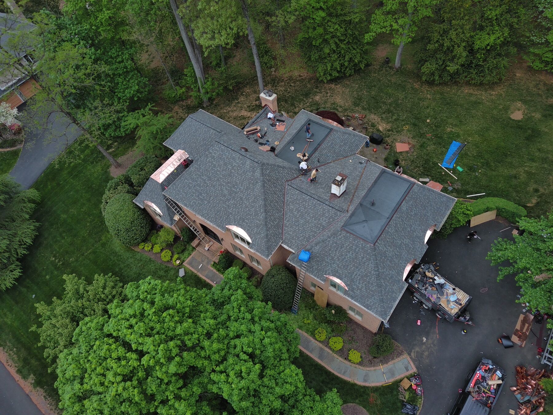 Designer asphalt shingle installation with copper dormer accents in progress