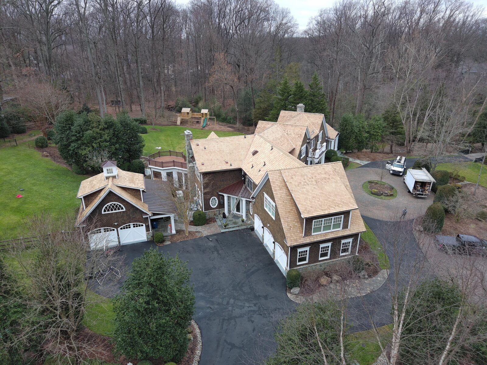 Aerial view of new natural cedar shake roofs on a main house and carriage garage