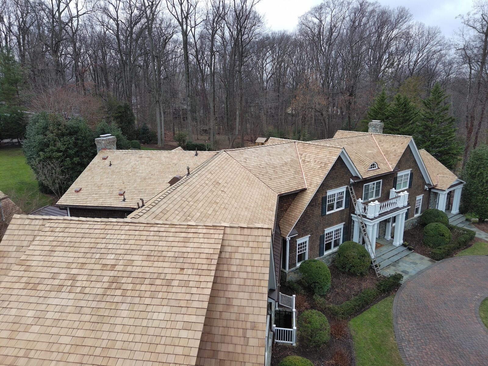 Freshly installed natural cedar shake roof on a hillside estate in winter