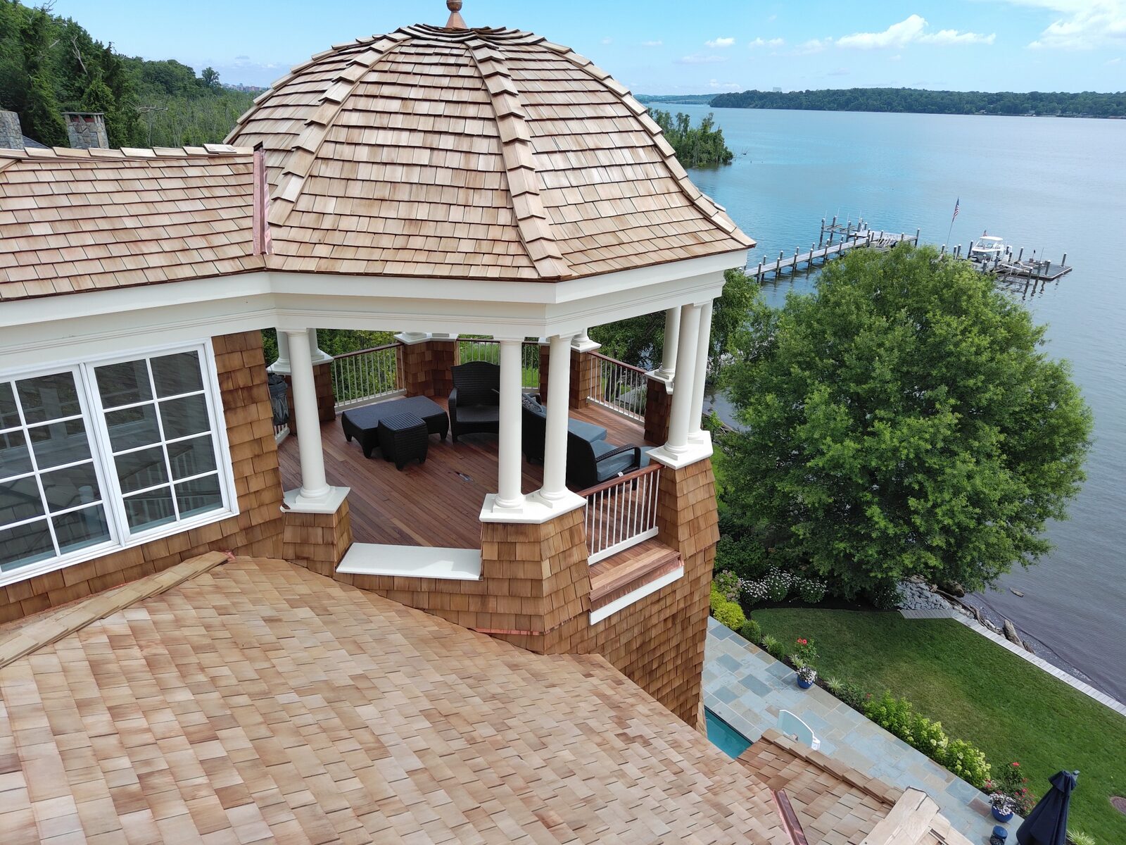 Cedar shake domed turret and shingle siding on a waterfront home with a dock