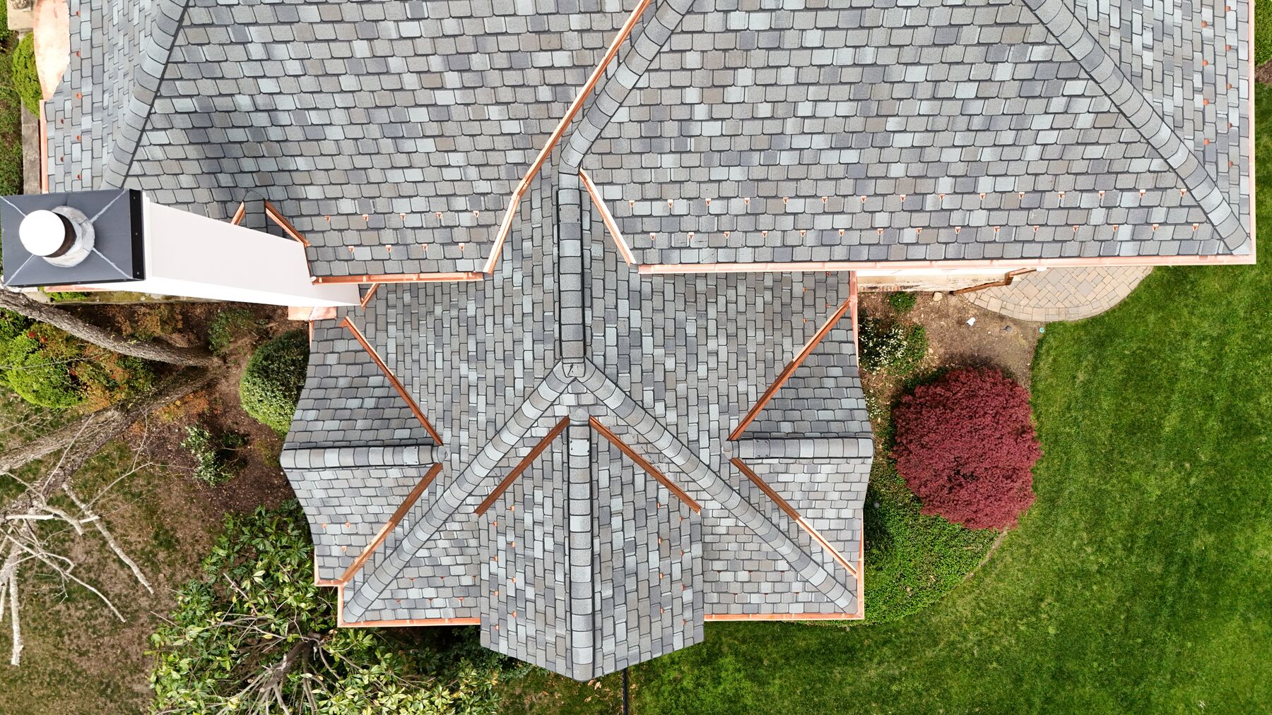 Top-down view of a designer asphalt shingle roof with copper valleys and snow guards