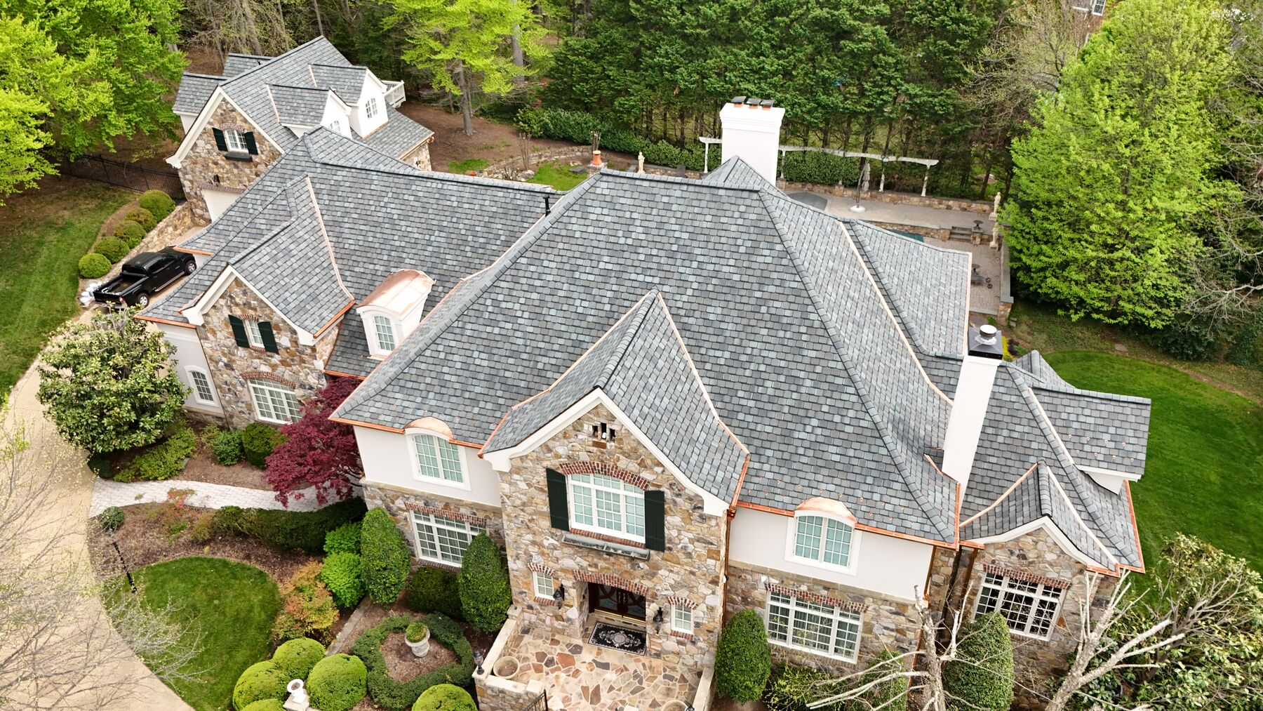 Stone manor with a designer asphalt shingle roof and copper accents